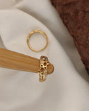 Gold ring with honeycomb design on a wooden stand against a beige fabric background