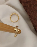Gold hoop earring and ring on a wooden stand with a soft fabric background