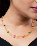 Close-up of a woman wearing a gold necklace with multicolored beads.