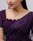 Woman wearing a purple saree with a plain background