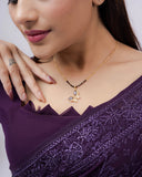 Woman wearing a purple saree with a gold necklace on a white background