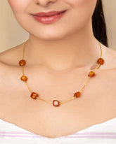 Necklace with brown beads worn by a person against a neutral background