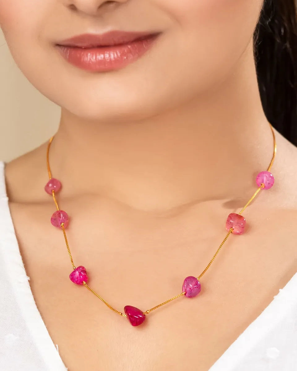 Necklace with pink beads worn by a model on a plain background