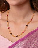 Close-up of a woman wearing a beaded necklace with a pink top.