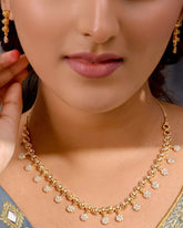 Close-up of a person wearing a gold necklace and earrings with a dark background