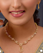 Woman wearing a gold necklace and earrings against a dark background