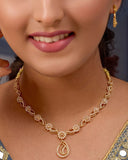 Woman wearing a gold necklace and earrings against a dark background