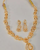Gold necklace and earrings set on a light gray background