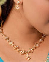 Woman wearing a gold necklace and earrings, with a close-up of the jewelry.