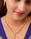 Close-up of a woman wearing a gold necklace and earrings with a blue top.