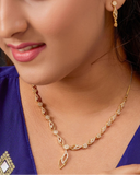 Woman wearing gold jewelry including a necklace and earrings.