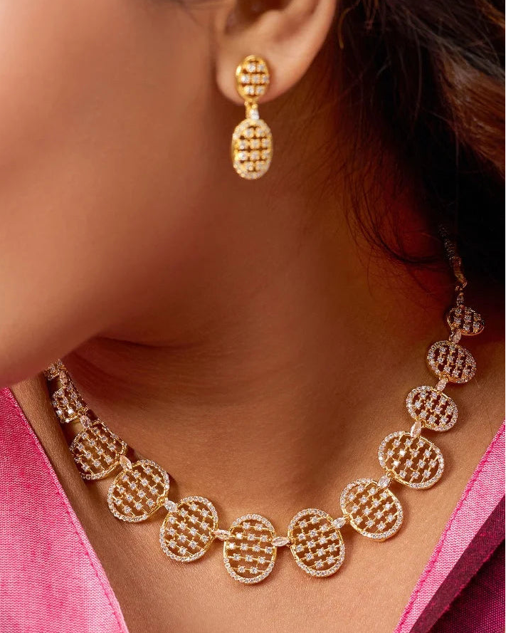 Close-up of a woman wearing gold earrings and necklace against a blurred background