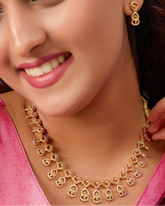 Woman wearing a gold necklace and earrings, smiling.