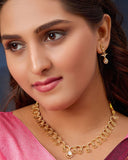 Woman wearing gold jewelry including a necklace and earrings against a dark background