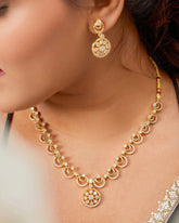 Gold necklace and earrings on a model with a blurred background