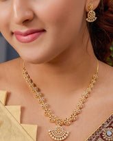 Woman wearing a gold necklace and earrings with a blurred background