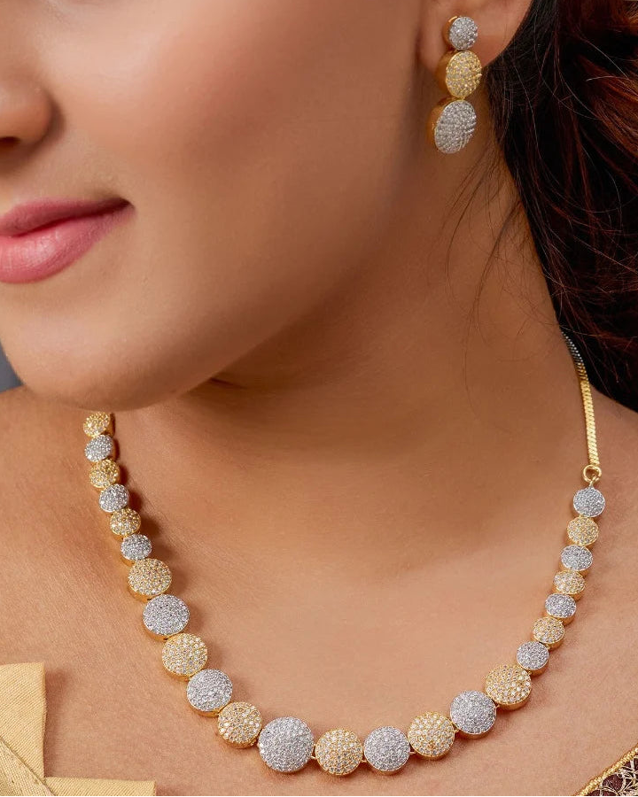 Close-up of a woman wearing a gold necklace and earrings with a blurred background