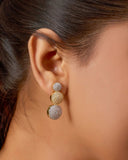 Close-up of a person wearing gold and silver spherical earrings.