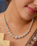 Necklace with gold and silver beads worn by a model against a neutral background