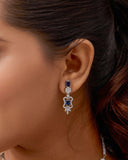 Close-up of a woman wearing a blue sapphire earring with a blurred background