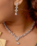 Close-up of a person wearing a diamond necklace and earrings.