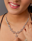 Close-up of a woman wearing a diamond necklace and earrings.