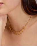 Gold necklace with tassel details worn by a person