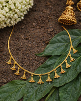 Gold necklace with pendant details on a leafy background