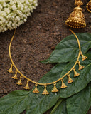 Gold necklace with pendant details on a leafy background