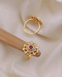 Gold earring with a red gemstone on a beige fabric background