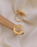 Gold ring with intricate design on a beige background