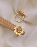 Gold sunflower-shaped earring on a wooden stick with a soft beige background