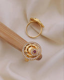 Gold ring with a red gemstone and diamond accents on a beige fabric background