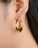 Gold hoop earring worn by a person with dark hair.