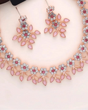 Jewelry set with necklace and earrings on a white surface with shells.