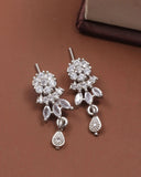 Silver earrings with clear stones on a brown surface