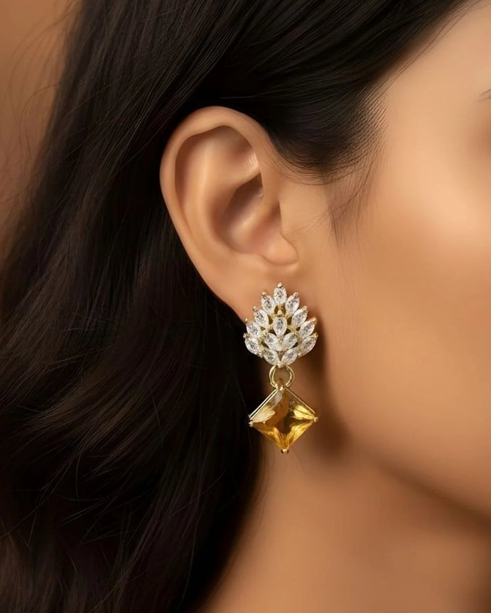 Close-up of a woman wearing a gold and diamond earring against a brown background