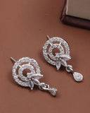 Silver earrings with intricate designs on a brown surface