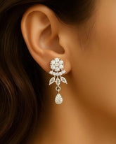 Close-up of an ear wearing a sparkling diamond earring with a dark hair background