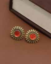 Pair of gold and red earrings on a brown surface
