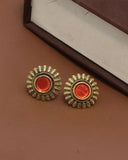 Pair of gold and red earrings on a brown surface