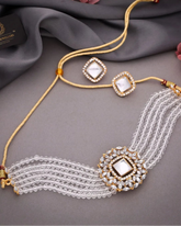 Decorative necklace with gold and white elements on a gray fabric background