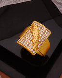 Gold ring with diamond accents on a black platform, draped with sheer fabric.