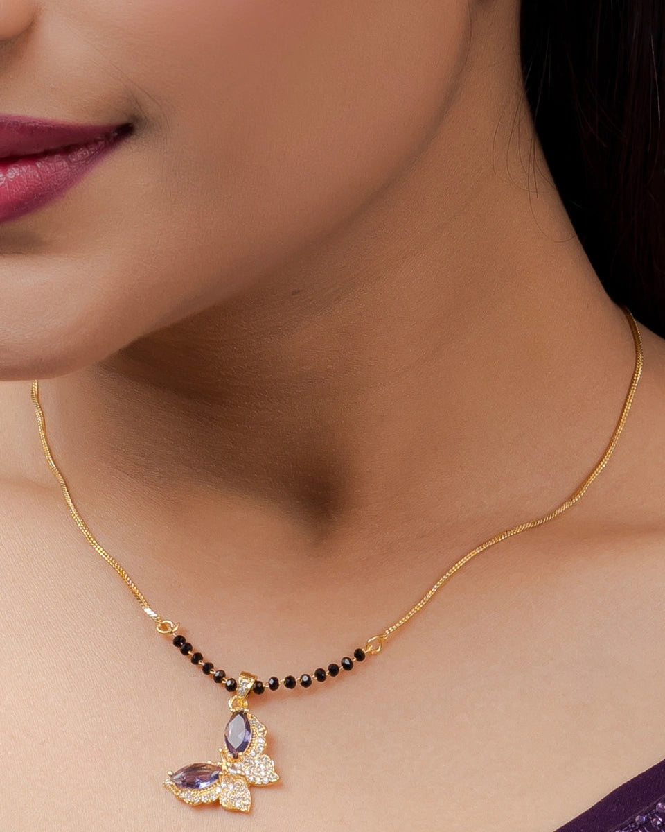 Close-up of a woman wearing a gold necklace with a pendant.