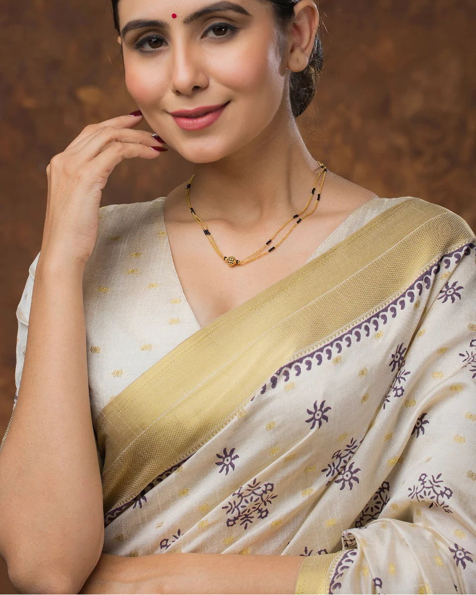 Woman wearing a traditional saree with a gold border against a brown background