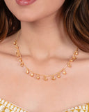 Gold necklace worn by a person with a blurred background