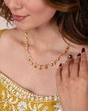 Woman wearing a gold necklace with a close-up of her hand and jewelry.