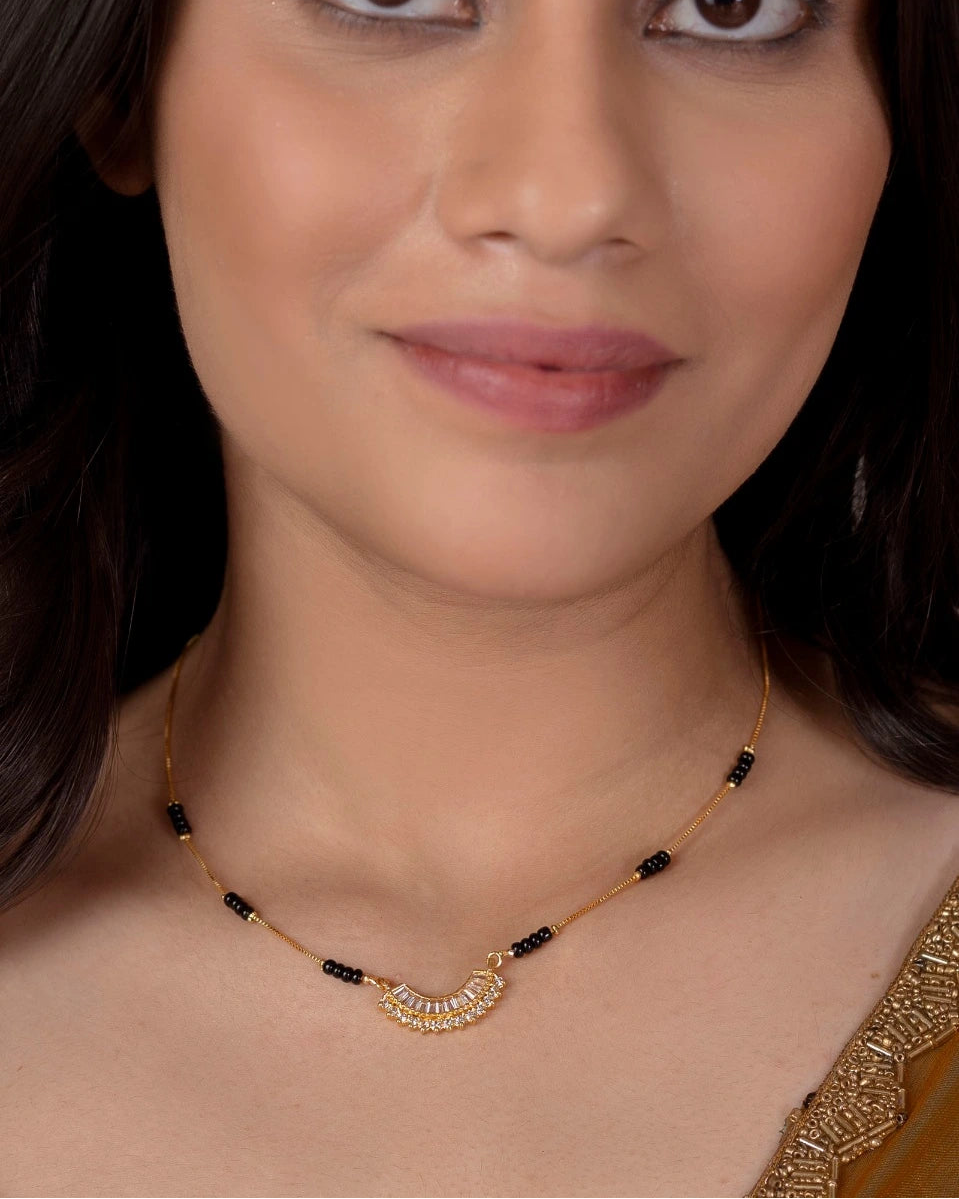 Woman wearing a gold necklace with black beads