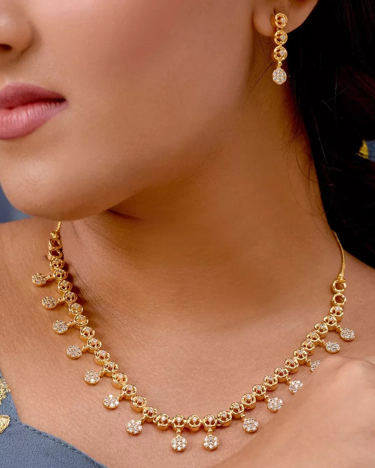 Close-up of a woman wearing gold jewelry including a necklace and earrings.