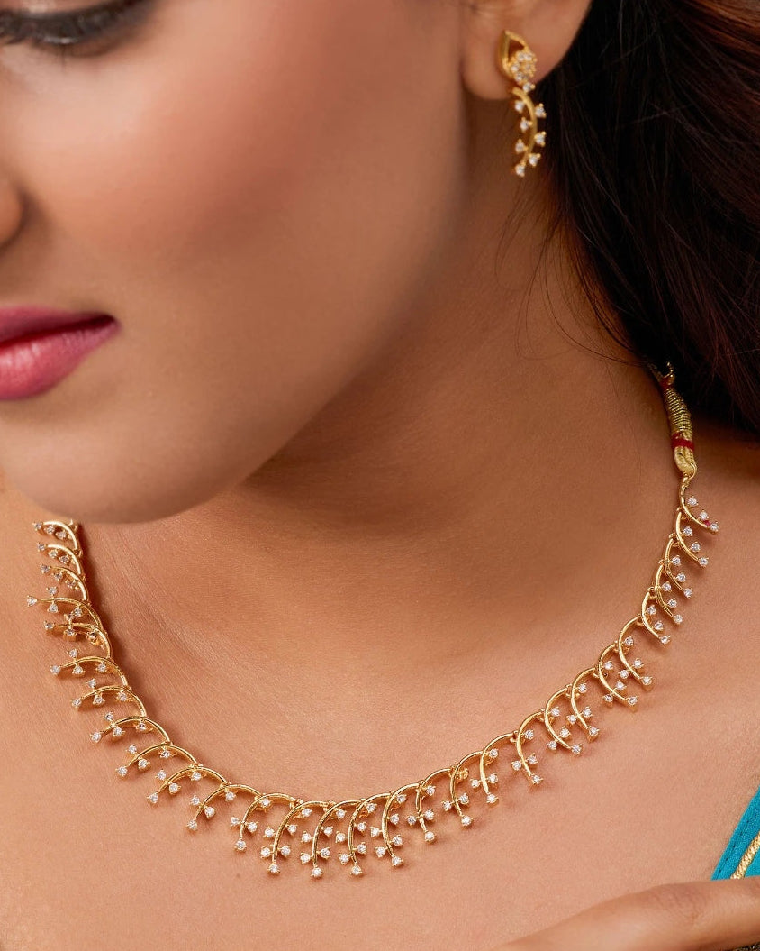 Woman wearing a gold necklace and earrings with a close-up of the jewelry.
